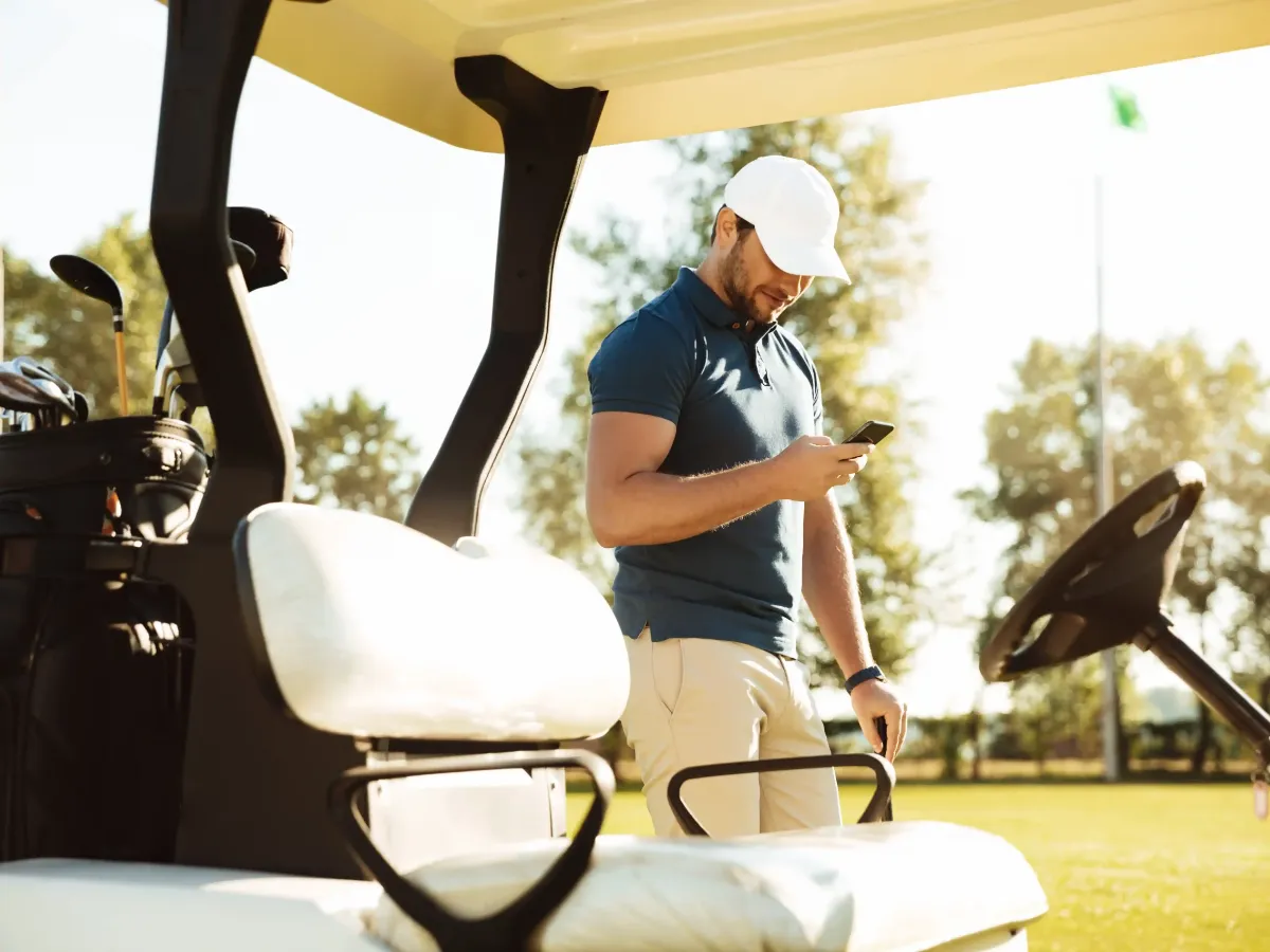 Golfista consultando su pedido de bolas de golf desde el móvil en el campo