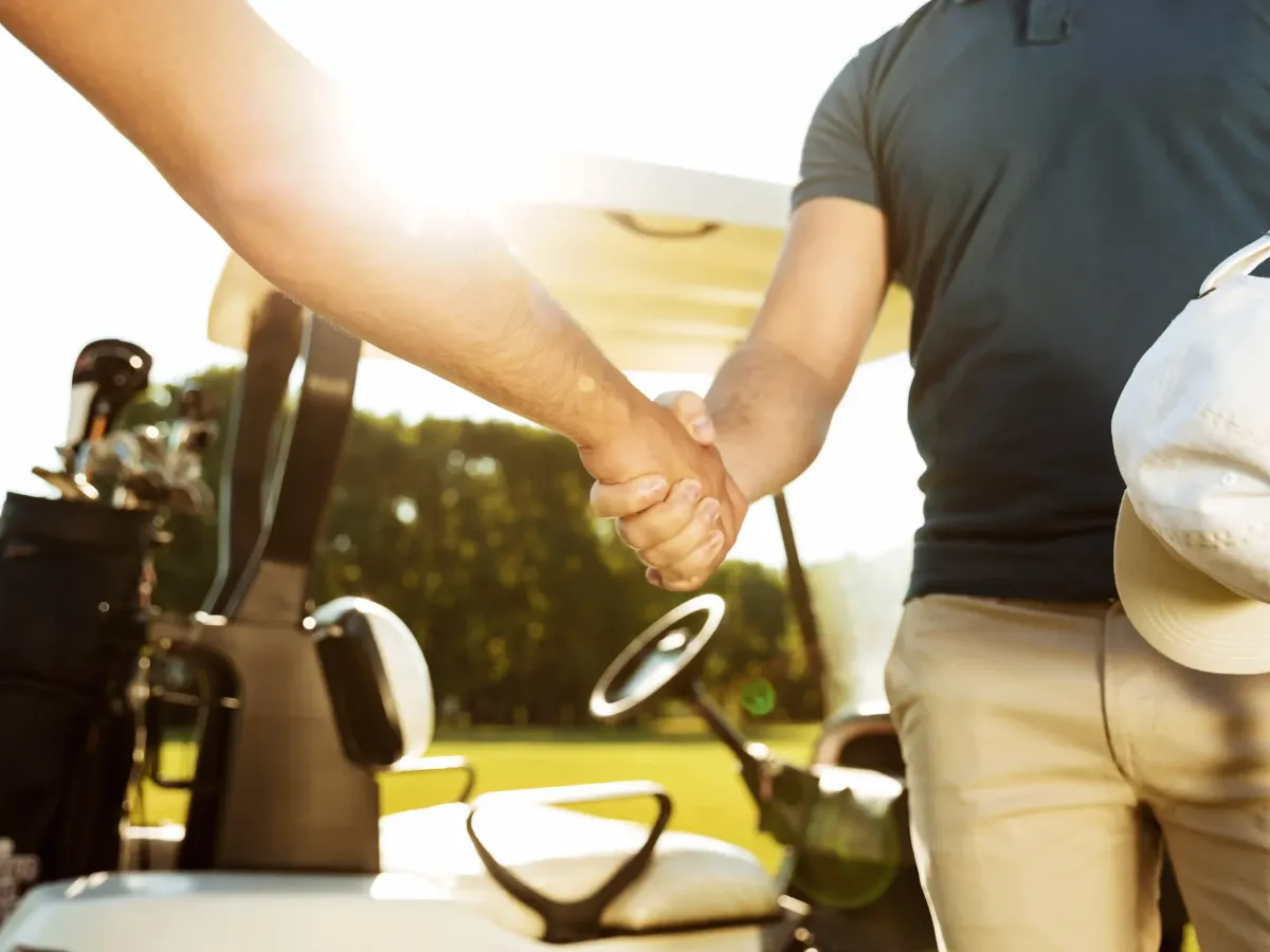 Dos jugadores de golf dándose la mano en señal de confianza y trato